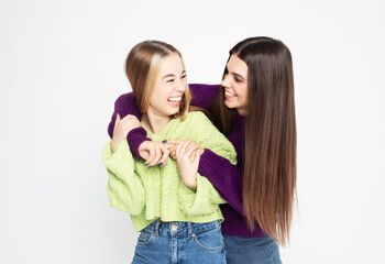 Studio shot of two young women friends wearing sweaters isolated over white background