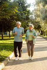Obraz premium Senior mature couple running together in the park looking at each other while jogging slimming exercises.