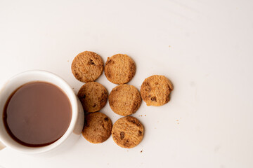 top view of chocolate chip cookies and a cup of hot chocolate, on a white background