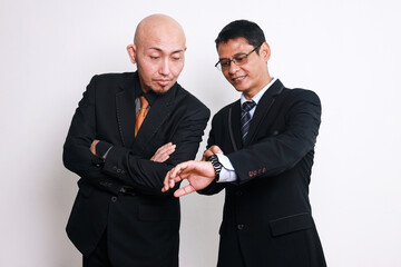 Two Asian businessmen checking time, late for business meeting or deadline over white background.