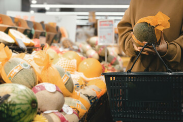 Asian women choose fresh fruits, compare and check ready to eat food labels, and choose a healthy...