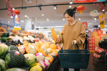 Asian women choose fresh fruits, compare and check ready to eat food labels, and choose a healthy...