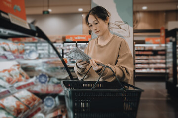 Asian women choose food in the aisle of the supermarket's fresh-keeping and freezing area, compare...