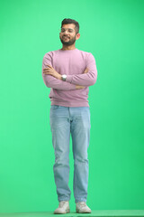 A man, on a green background, in full height, crossed his arms