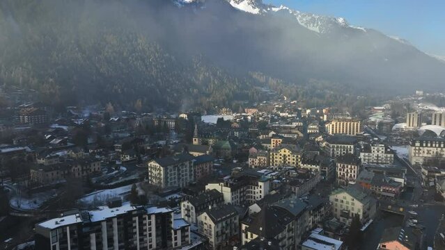 Aerial Drone fly over of Chamonix ski town on a bright winter day with fog. European ski village in the alps mountains.  