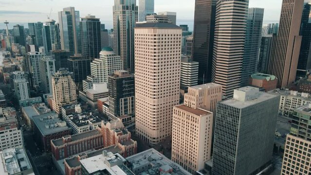 Aerial orbital parallax around beige and modern sleek silver downtown skyline buildings of Seattle Washington