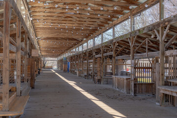 Empty open air farmers market wooden stalls within a pavilion on a bright sunny day. 
 