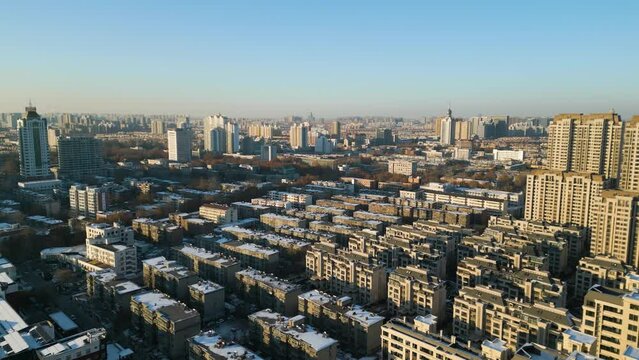 Sunset light casts strong golden glow across dense apartment building complex, aerial establish