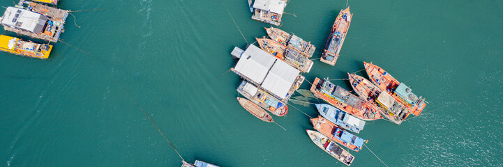 Aerial view of a bustling fishing harbor with boats and floating structures, illustrating the concept of maritime economy and seafood industry