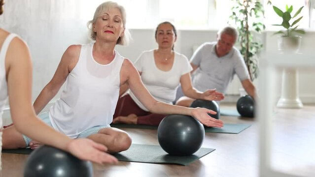 Group of elderly active people doing soft ball exercises during group pilates class in fitness studio. High quality 4k footage