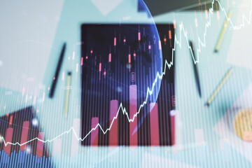 Multi exposure of abstract creative financial graph with world map and modern digital tablet on background, top view, forex and investment concept