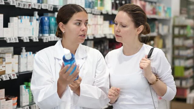 Female pharmacist advises a girl who came to the pharmacy to buy a therapeutic cosmetics 