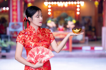 Beautiful Asian woman wearing a traditional red cheongsam on Chinese New Year. Young woman hand...