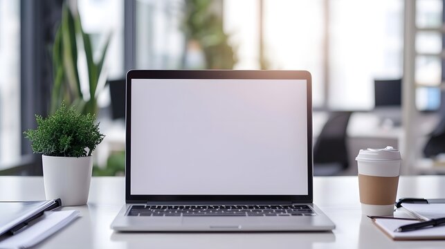 Laptop with blank screen on desk. isolated on blurred background. workbench with green plant and cup of coffe. for template, presentation. copy space. mockup. business concept. 