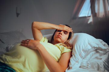 Tired Pregnant Woman Resting in Bed Feeling Uncomfortable. Unhappy mother to be suffering from...