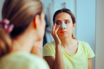 Woman Using a Deep Cleansing Pore Nasal Strip for Blackheads. Girl applying cosmetic treatment at...