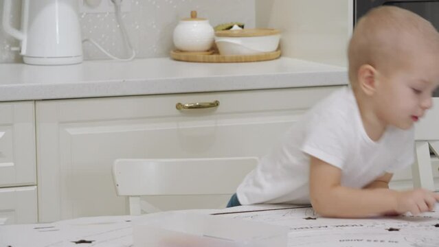3-year-old child drawing with felt tip pens on large sheet of cardboard. Cute little boy drawing at home.
