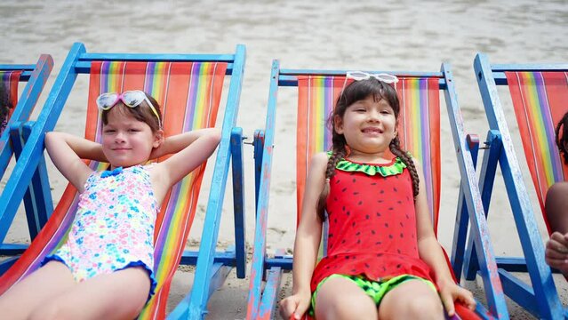 Group of Diversity children kids enjoy and fun outdoor lifestyle travel ocean on summer beach holiday vacation. Little child boy and girl friend resting on beach chair together at the sea in sunny day