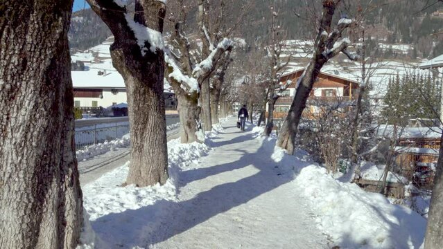 A person walks along a snow-covered path in Innichen - San Candido, South Tyrol, Italy