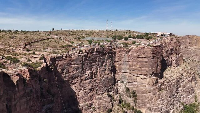 View of buildings on edge of cliff, Asir Mountains, Saudi Arabia. Aerial backwards