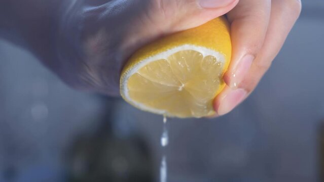 The hand of a chef squeezing a fresh lemon. Slow motion.