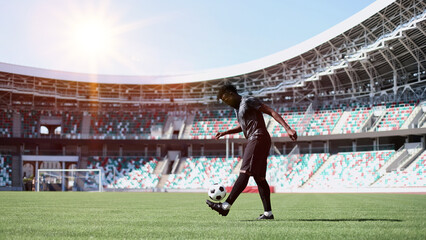 African American man playing football on the stadium field. A man runs with a soccer ball across...