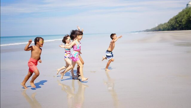 Group of Children kid enjoy and fun outdoor lifestyle travel ocean on summer beach holiday vacation. Diversity child boy and girl friends running on the beach and playing sea water at tropical island.