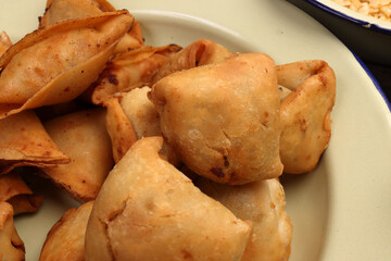 Deep fried samosa singara stuffed with potato minced meat vegetable benglai snacks on enamel tin metal plate