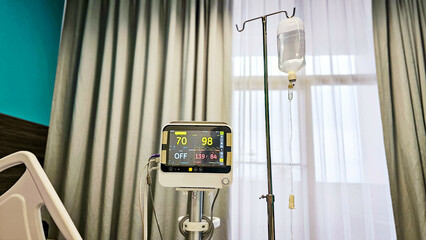 Vital signs monitor showing Heart rate and blood pressure of patient in patient room with saline...