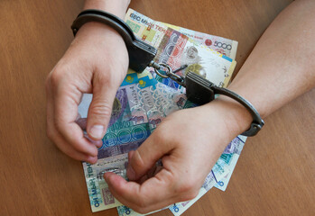Concept of hands in handcuffs lie on the Kazakh tenge.