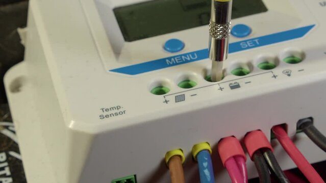 Worker ensures wires are firmly attached to solar charge controller