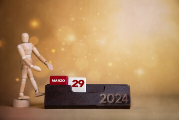 Calendar brilliance in March: Wooden character directs to the twenty-ninth day amidst a warm-toned, bright background.