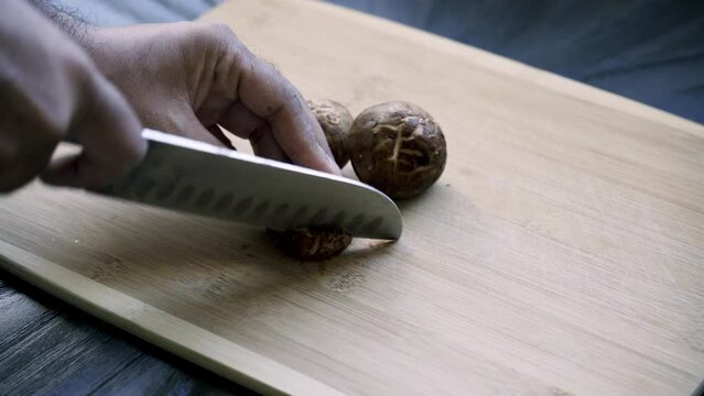 Cutting shiitake mushrooms on cutting board Making a shitake mushroom and purple potato breakfast dish for vegan plant based lifestyle assorted peppers sweet potato