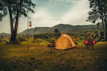 A tent on the grass with a view of the mountains in the background and sunlight. Holiday, Travel,...