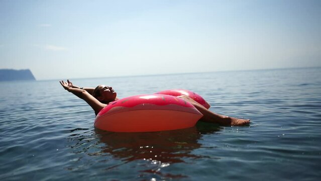 woman floats on an inflatable donut mattress. Happy woman relaxing and enjoying family summer travel holidays travel on the sea.
