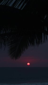 Vertical timelapse. Ocean at sunset. Red sun sets over the horizon.