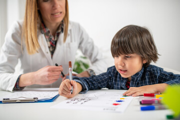 A little boy doing a cognitive assessment test for preschoolers, monitored by a pediatric...