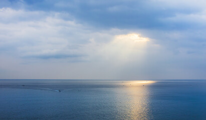 Sunlight pouring through the clouds reflects on the surface of the sea. Morning sunrise scenery on the sea