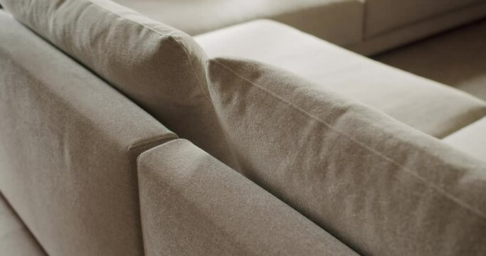 Cropped view of female hand touch couch upholstery while passing by in living room. Closeup on woman gently check fabric of new sofa. Modern furniture at home