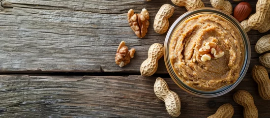 Fotobehang Delicious Peanut or Ground Nut Spread Over a Rustic Wooden Background - Nutty, Nutty, Nutty © TheWaterMeloonProjec