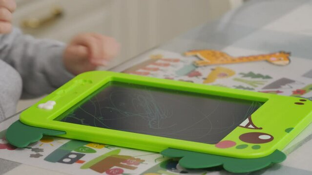 3-year-old child drawing with pen on electronic drawing writing board. Little boy playing with drawing tablet for kids.