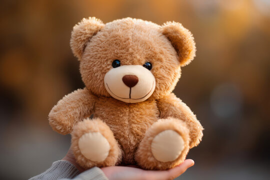 
Close-up photo of a fluffy teddy bear in the tiny hands of a toddler against a soft-focus background