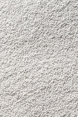 Vertical image of a lot of white plastic polymer granules..