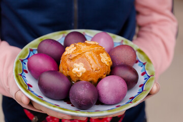 Fototapeta na wymiar Easter cake and eggs on a plate in children's hands