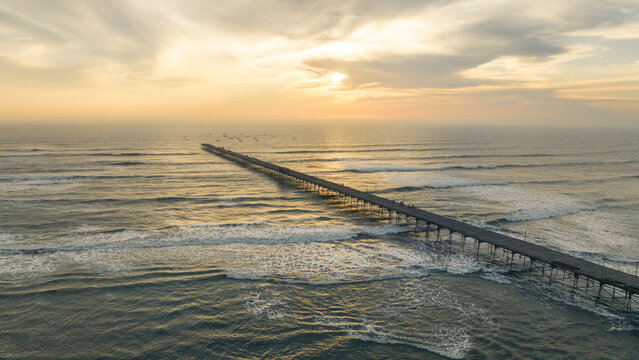 Pier on the beach on a colorful and calm sunset. Puerto Eten, Peru.