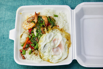 Stir-fried seafood and fried egg with holy basil in foam box