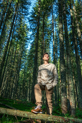 Fototapeta na wymiar Young Male Hiker Looking Away While Standing Against Trees in Forest
