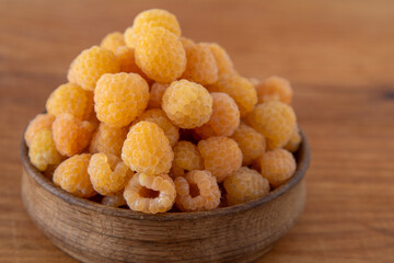 Yellow raspberries in a wooden bowl on the table. Summer berries background. Vitamin food, berry harvest. Healthy nutrition.