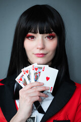 Female cosplay character with black hair, red eyes, a red jacket, and a set of playing cards