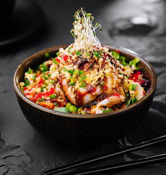 Salad with eel and couscous on black bowl